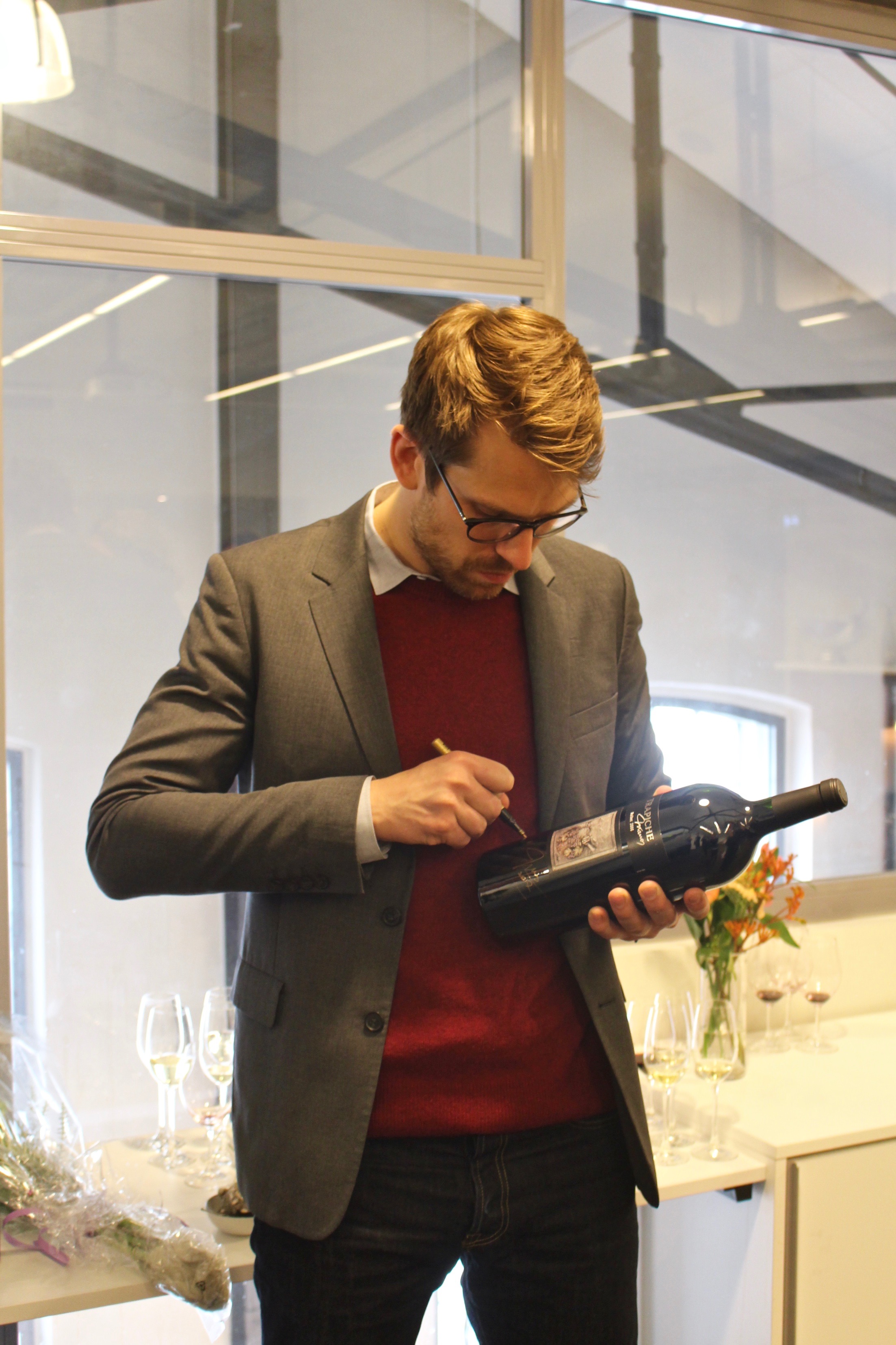 Arvid Rosengren signerar vinflaskor till en välgörenhetsauktion.